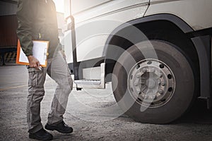 Truck driver holding clipboard his inspecting daily checklist safety of a truck wheels and tires. truck inspection and maintenance