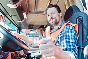 Truck driver sitting in cabin giving thumbs-up photo