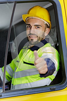 Truck driver man sitting in cabin giving thumbs-up