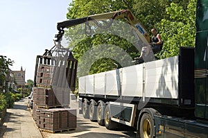 Truck driver, road builder unload lorry paving stones