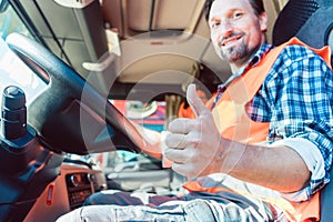 Truck driver sitting in cabin giving thumbs-up