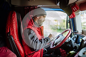Truck driver sitting in truck, holding tablet, looking at cargo details, delivery schedule.