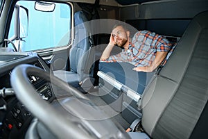 Truck driver sleeping on bed inside truck cabin interior. Trucker lifestyle.