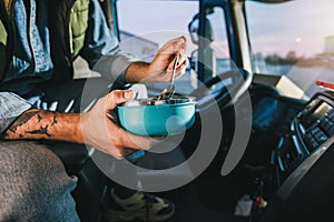 Truck driver taking a break from long drive to eat some food from container