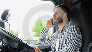 Truck driver talking by mobile phone while sitting in cabin of his truck. Right hand drive car