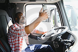 truck driver video call on smartphone in cockpit. Trucker Asian young man beard parked for coffee break after long drive