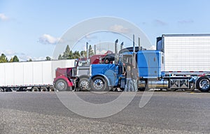 Truck drivers exchange views on the strengths and weaknesses of their big rigs semi trucks standing on truck stop photo