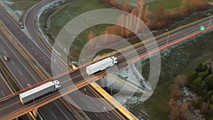 A truck drives over a bridge crossing a high-speed highway with heavy traffic