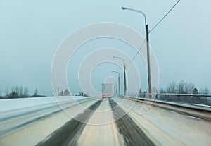 Truck drives with tail and stop lights on the winter road in a snow storm in the twilight when snow is flying. Conce