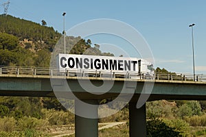 A truck is driving across the bridge, with the inscription on the trailer - consignment.