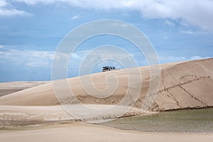 A truck driving in the back of a unique white sand dunes of Lencois Maranhenses in north Brazil