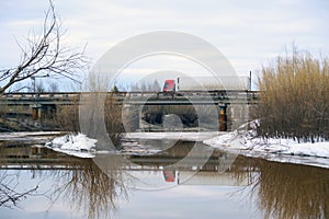 Truck driving on a bridge over river in the spring.