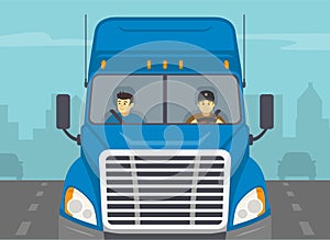 Truck driving on a city road. Close-up view of a blue semi-trailer driver and his co-driver.