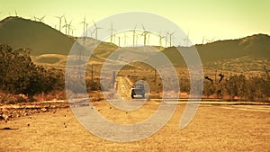 Truck Driving Down Desert Road from Wind Farm