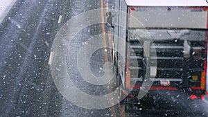 Truck driving on a highway with wet slippery asphalt during a snow storm