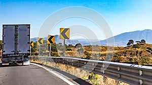 Truck driving on a road with dangerous curve signage