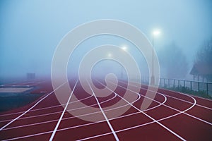 Truck and Field concept photo. Red athletics track in morning mist. Running photo, white edit space