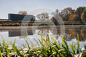 Truck goes on the road in autumn. car transport . Truck with semi-trailer in gray color. Transport truck drives in autumn by the