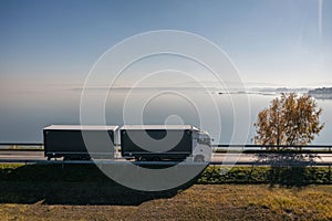 Truck goes on the road in autumn. car transport . Truck with semi-trailer in gray color. Transport truck drives in autumn by the