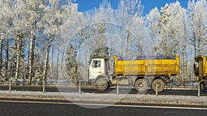 Truck goes on winter road. Van in the road of winter. Lorry car and cold landscape. Roadway and route snowy street trip