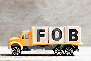 Truck hold block in word FOB abbreviation of Free On Board on wood background