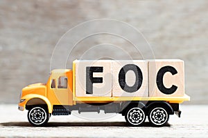 Truck hold block in word FOC Abbreviation of Free of charge on wood background photo