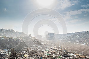 Truck at the huge garbage dump full of smoke, litter, plastic bottles,rubbish and trash at the Thilafushi local tropical island