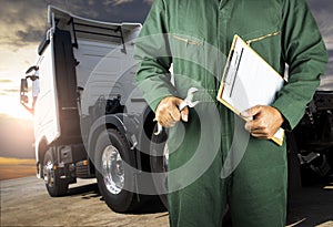 Truck inspection repairing and maintenance. Professional auto mechanic holding wrench and clipboard his checking of semi-truck.