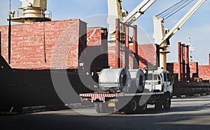 Truck load steel coils alongside big ship