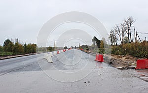 truck loader is driving on the new repaired asphalt road with plastic enclosures.