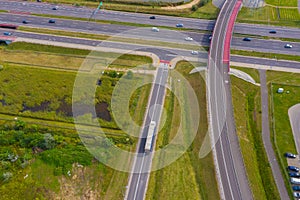 Truck logistic aerial. Trucks motion by the highway intersection road between fields. View from drone