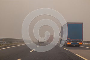 Truck or lorries and one van overtaking at a dangerous time with thick fog on a motorway in italy, europe