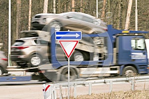 Truck with new cars on the road with road sign