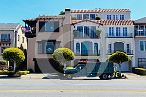 A truck parked near a beautiful penthouse with trees in fine weather against a blue sky