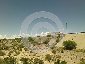Truck passes over an overpass with clouds seeming to stream behind from train photo