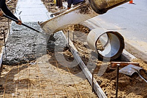 Truck pouring cement concrete casting on reinforcing metal bars of sidewalk