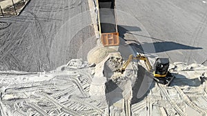 The truck pours sand on the site. Excavator scooping sand bucket.