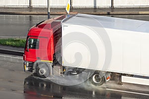 Truck with refrigerated trailer driving on wet asphalt after rain