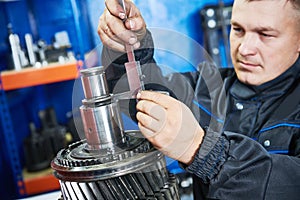 Truck repair service. serviceman measuring gear shaft of gearbox photo