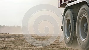 Truck rides on sand quarry road. Scene. Dump truck driving on yellow dirt road in countryside. Large trucks on