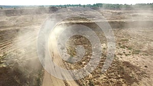 Truck rides on sand quarry road. Scene. Top view of dump truck driving on yellow dirt road in countryside. Large trucks