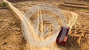 Truck rides on sand quarry road. Scene. Top view of dump truck driving on yellow dirt road in countryside. Large trucks