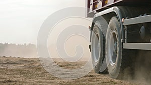 Truck rides on sand quarry road. Scene. Top view of dump truck driving on yellow dirt road in countryside. Large trucks