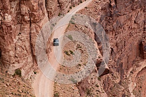 Truck riding on Scenic Dirt Road surrounded by Red Rock in Desert Canyon.