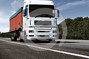 Truck on the road, front view, empty space on a red container - concept of cargo transportation, trucking industry