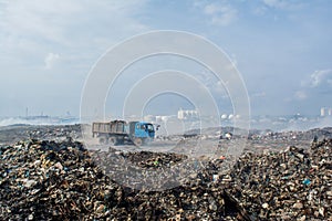 Truck on the road at the garbage dump full of smoke, litter, plastic bottles,rubbish and trash at tropical island