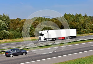 Truck with semi-trailer driving along highway on the blue sky background.