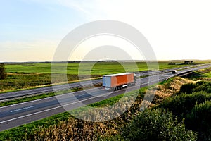 Truck with semi-trailer driving along highway on the sunset background. Goods delivery by roads. Services and Transport logistics