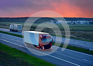 Truck with semi-trailer driving along highway on the sunset background. Goods delivery by roads. Services and Transport logistics