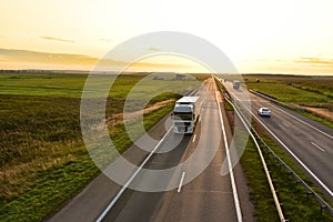 Truck with semi-trailer driving along highway on the sunset background. Goods delivery by roads. Services and Transport logistics